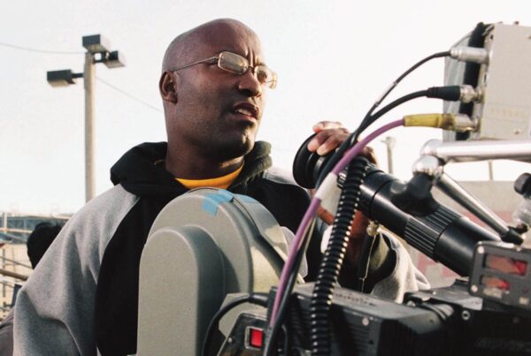 John Singleton directing behind a camera on the set of a film