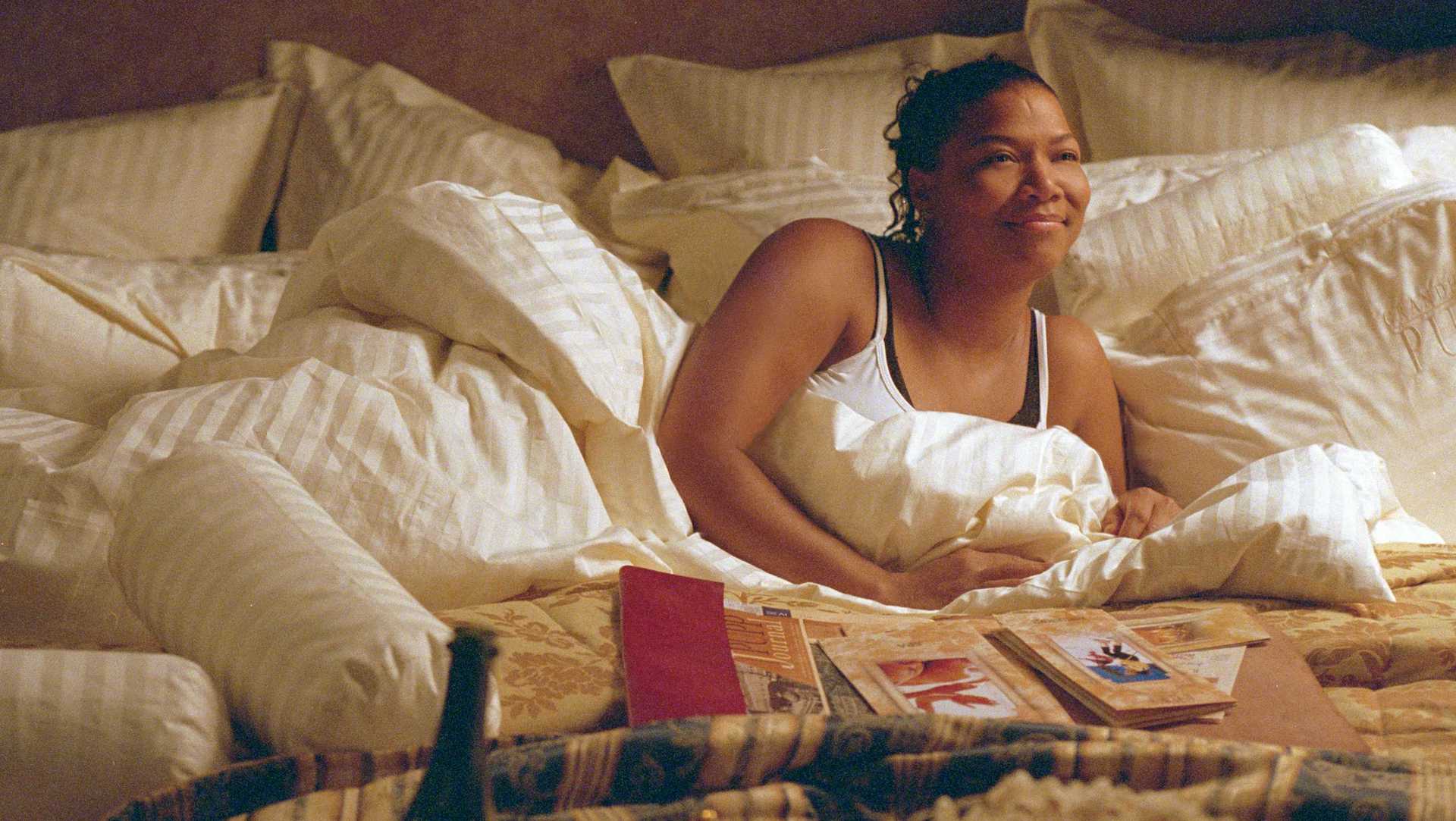 Georgia (Queen Latifah) laying in bed with travel books in 'Last Holiday'