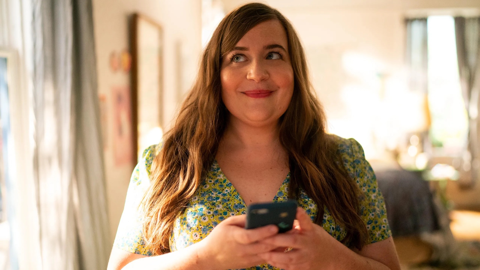 Annie (Aidy Bryant) smiling as she holds her smartphone in 'Shrill,' How You Can Embrace Size Inclusivity in Your Screenplay