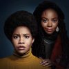 Hazel-May (Ashleigh Murray) standing behind Nelly (Sinclair Daniel) in 'The Other Black Girl'