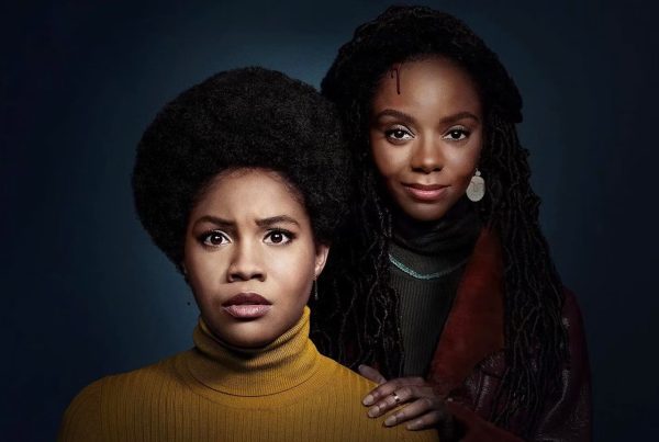 Hazel-May (Ashleigh Murray) standing behind Nelly (Sinclair Daniel) in 'The Other Black Girl'